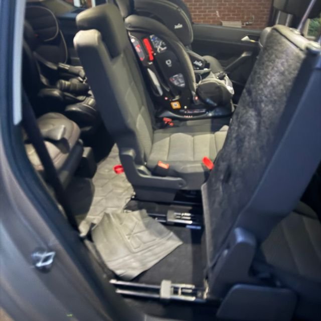 The inside of a family car, rows of child car seats and folded seats, no one inside